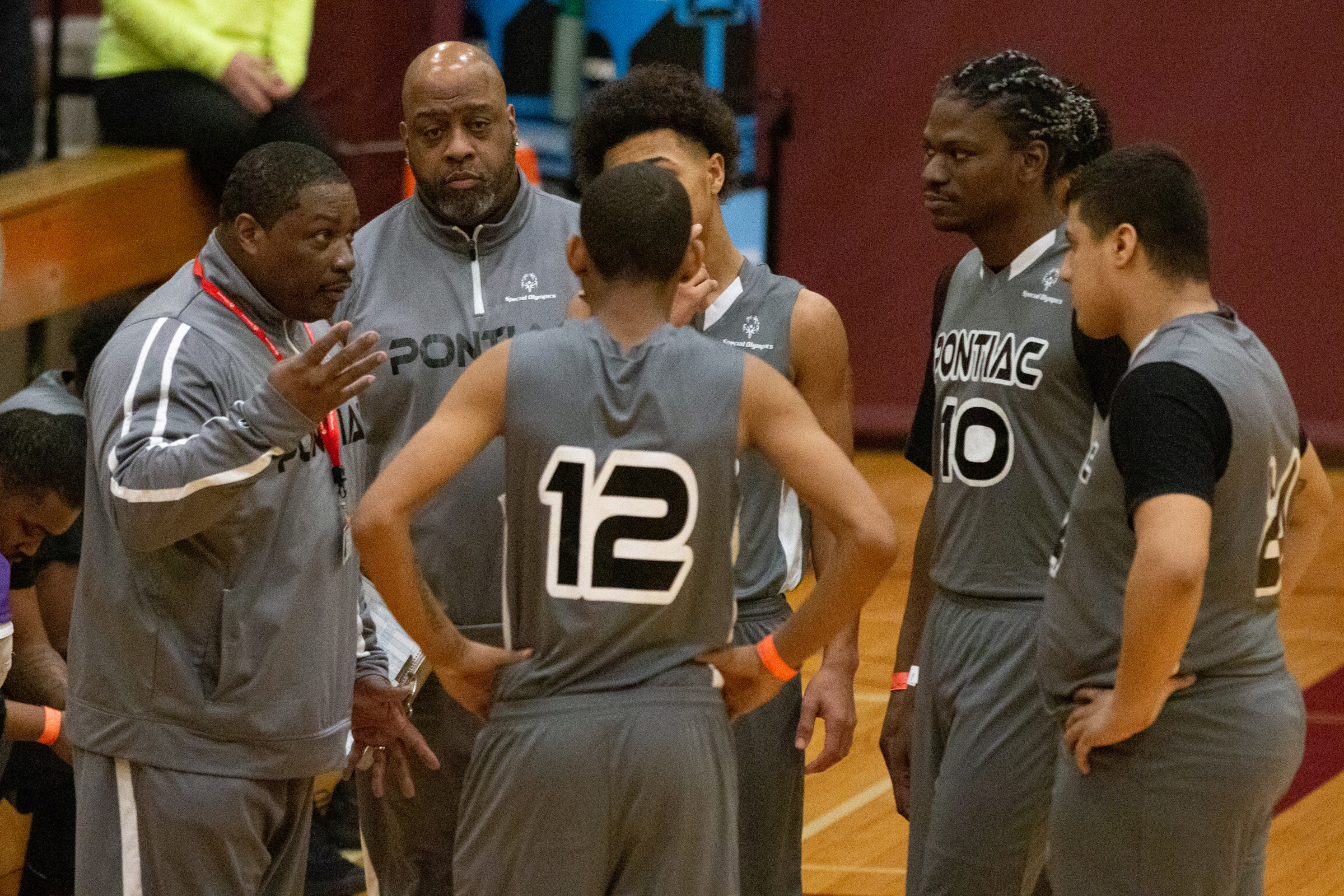 A basketball team huddles around its coaches during a timeout.