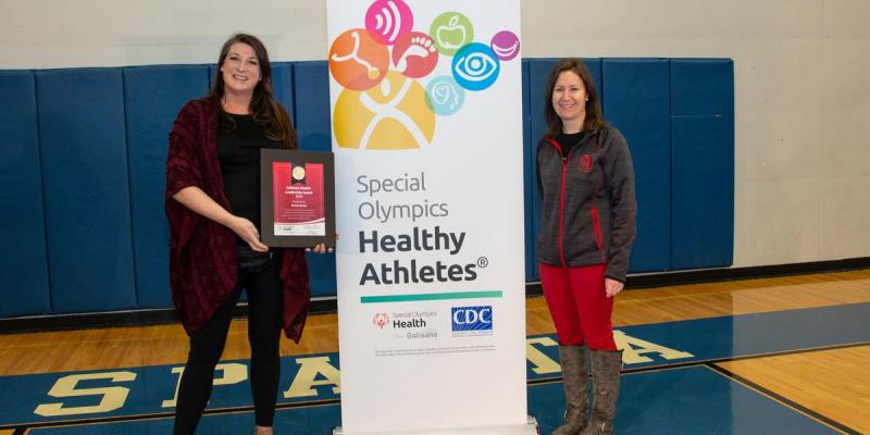 Renne Wyman and Heather Burke stand in front of a Healthy Athletes bannger