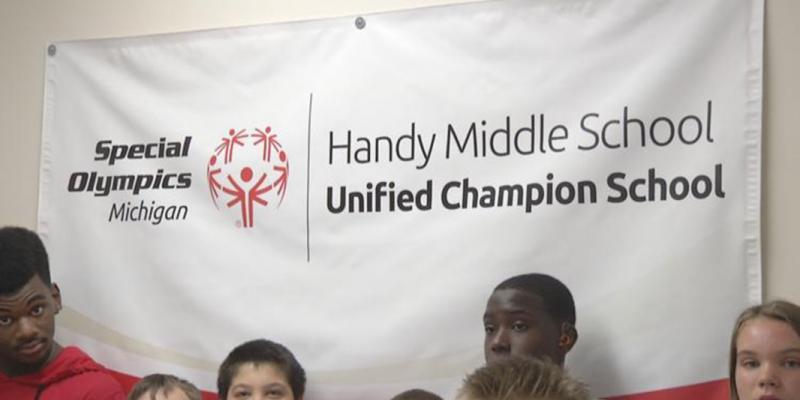Handy Middle School students stand near a Special Olympics banner