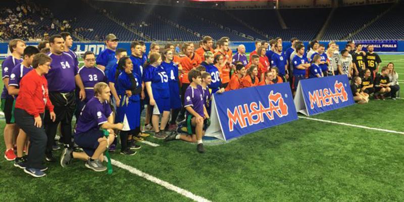 Six Unified high school flag football teams pose for a photo at Ford Field